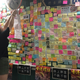 Crystal, a volunteer, puts up a notice directing people to continue putting up sticky notes elsewhere in the underpass due to a lack of space.